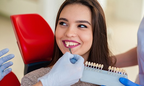 Woman's smile compared to porcelain veneers shades during cosmetic dentistry consultation