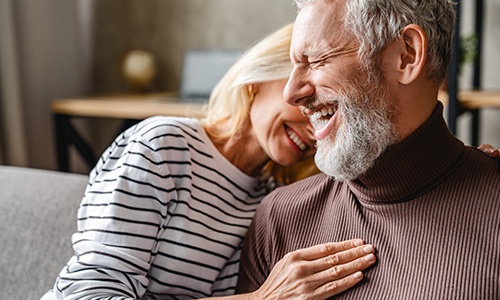 Man and woman smiling together after dental implant tooth replacement