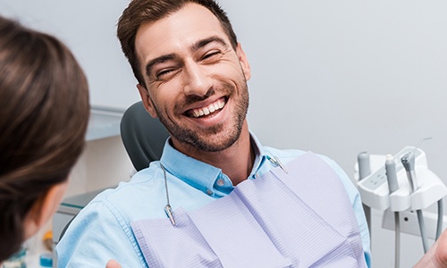 Man in dental chair smiling at dentist