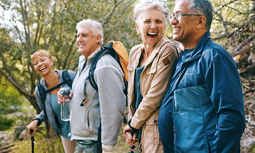 Group of senior friends smiling while hiking through woods