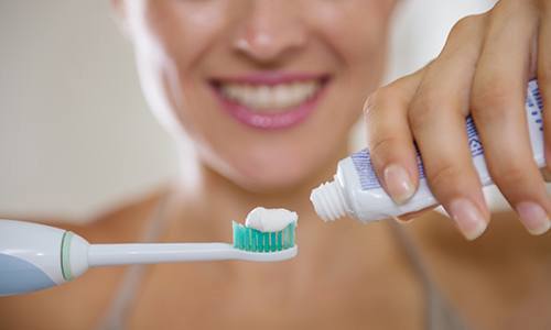 a patient applying toothpaste to her toothbrush