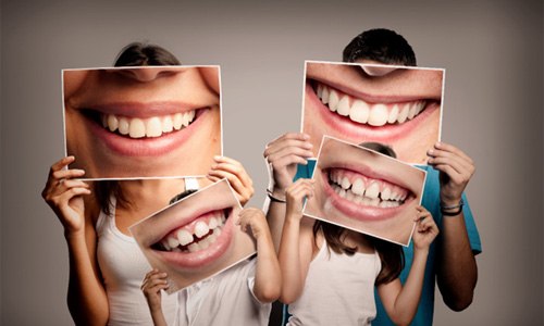 Family holding smile photos after visiting Webster family dentist 