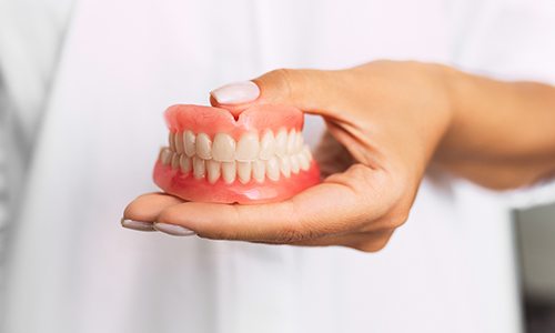 Hand holding full set of dentures