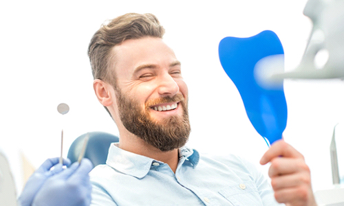 Man admiring his smile after teeth whitening in Webster