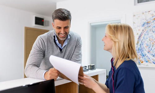 Dental team member assisting patient at front desk