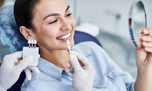 Patient with veneers in Webster looking at smile in mirror