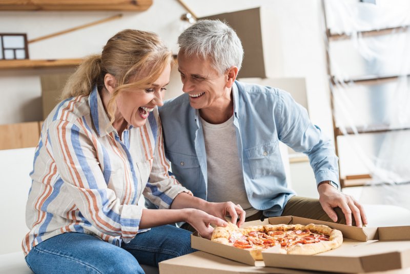 Mature couple smiling while eating pizza