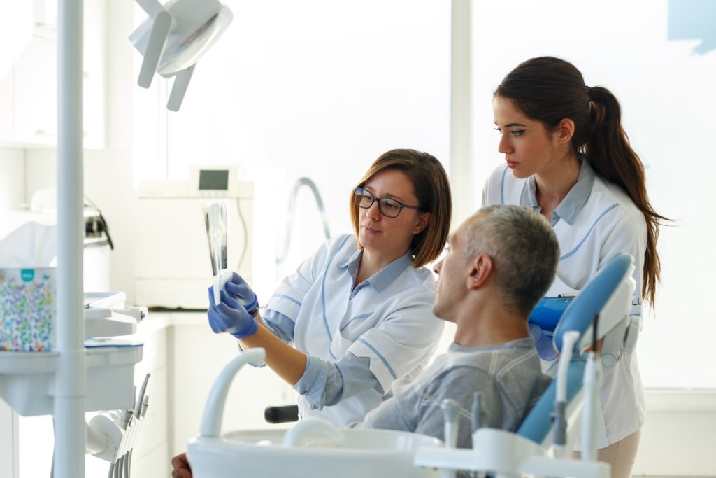 Dentist and dental assistant showing patient X-ray