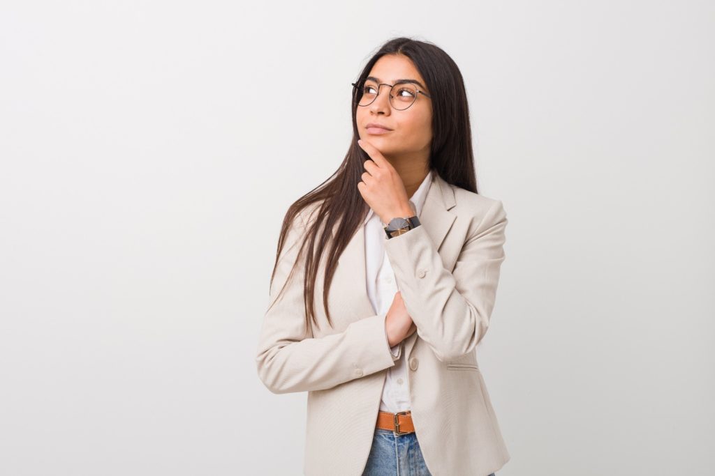 Woman in blazer and glasses wondering