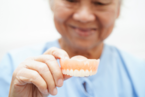 a patient holding their dentures and smiling